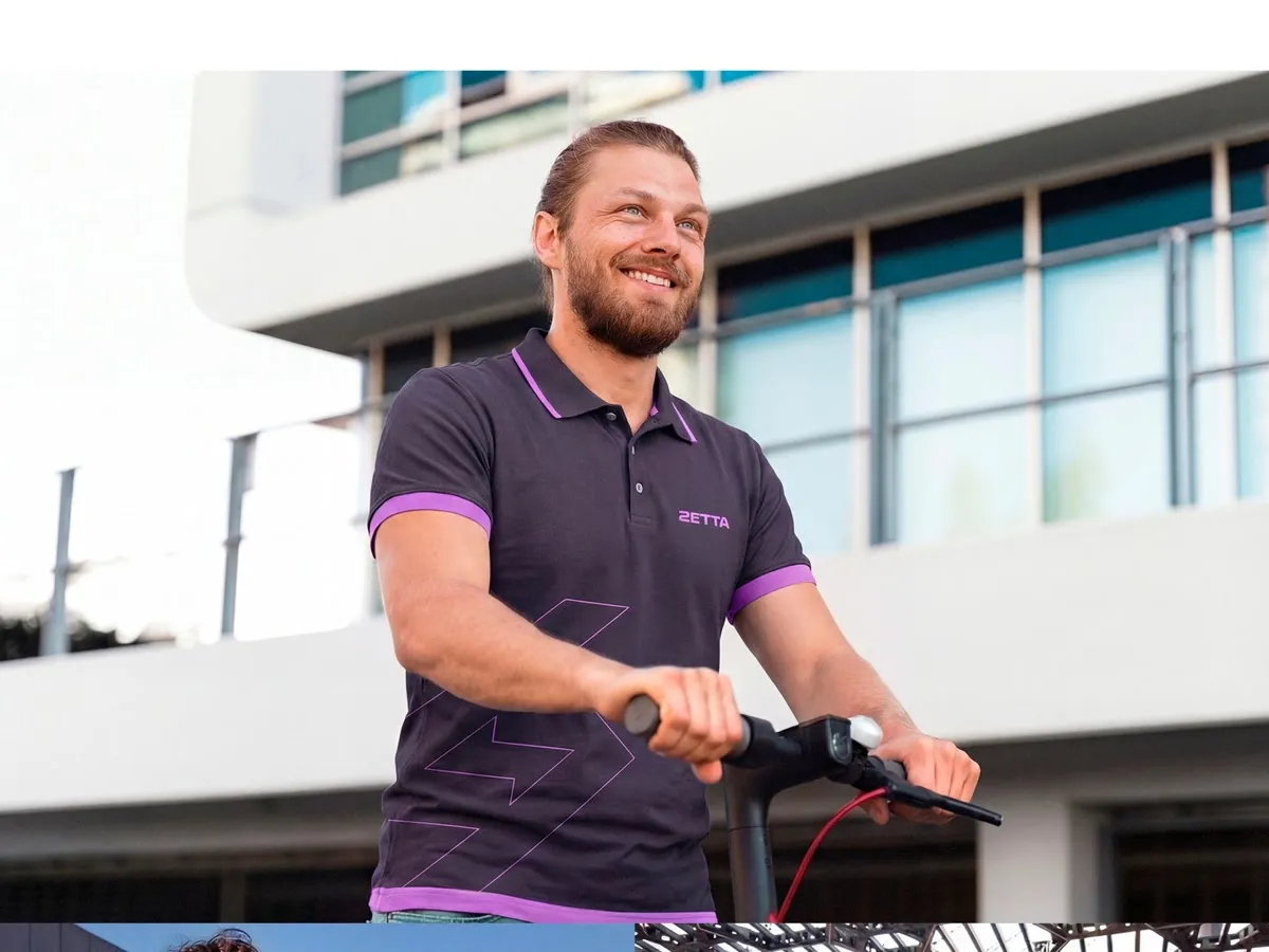 Homem sorrindo em um patinete elétrico, de camisa polo com a marca Zetta